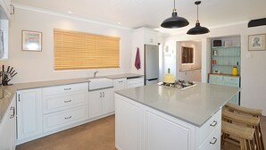 Uma cozinha moderna com armários brancos, uma ilha grande e iluminação pendente.