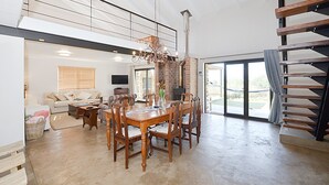 Uma sala de estar ampla com mesa de jantar, cadeiras, lareira e escada.