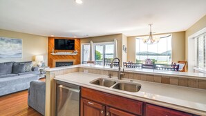 Een moderne keuken met een groot schiereiland, inbouwapparatuur en een eethoek met uitzicht.