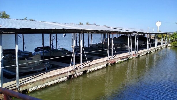 A covered boat dock with several boats moored underneath.