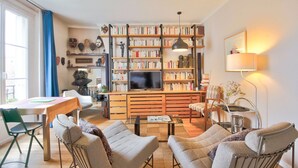 Un salon chaleureux avec une table basse en bois, des fauteuils confortables, une bibliothèque et un téléviseur à écran plat.