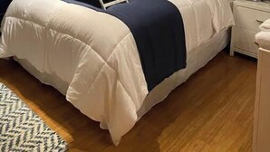 A neatly arranged bedroom with a bed, bedside tables, a nightstand, a lamp, a painting, and a window with starfish decorations. - Awesome suite, 100 steps to the ocean! (Kitty Hawk)