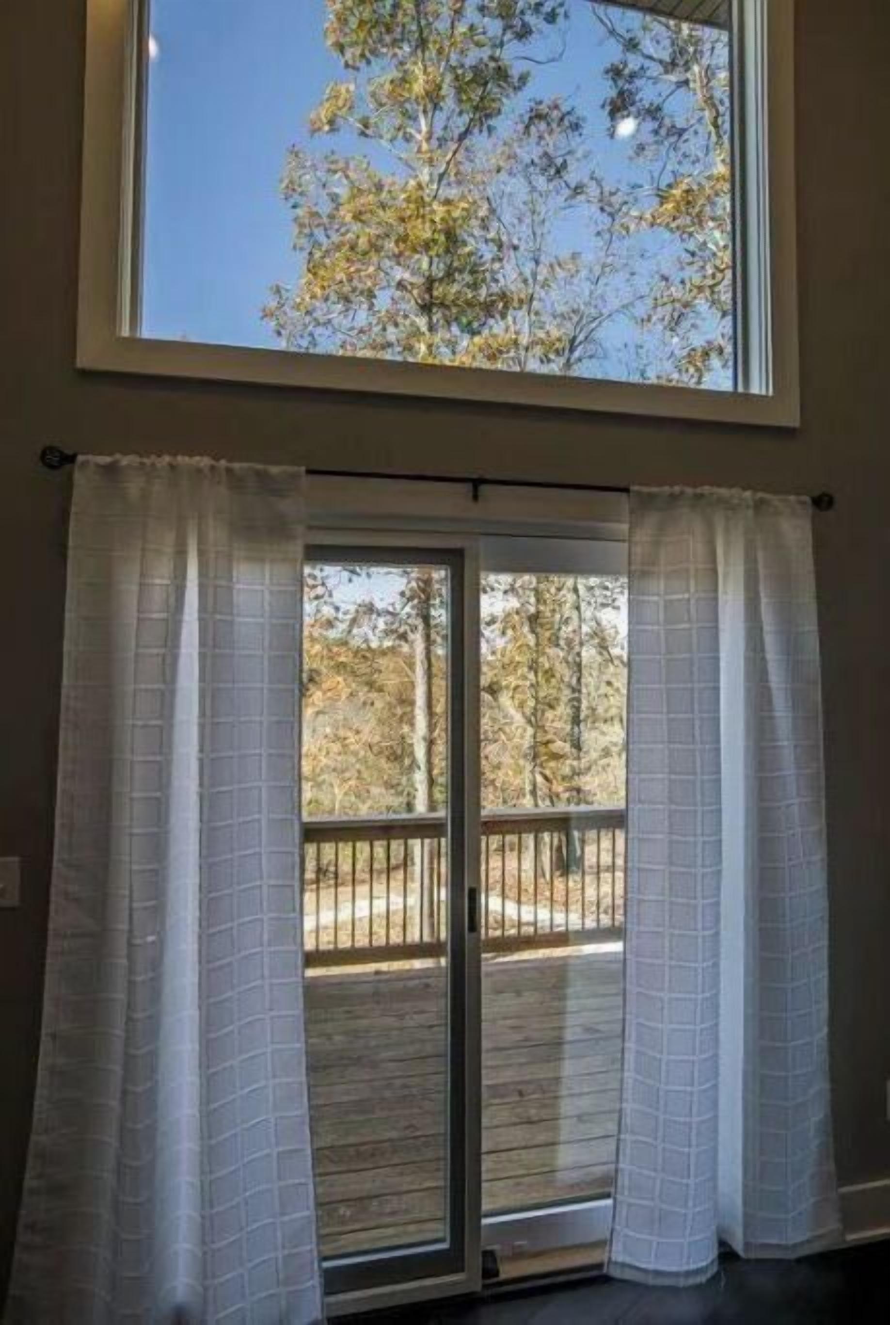 Una habitación con un ventanal grande que da a una terraza con barandilla de madera.