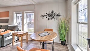 Una sala moderna con una mesa redonda de madera, un sofá gris y un elemento decorativo en la pared.