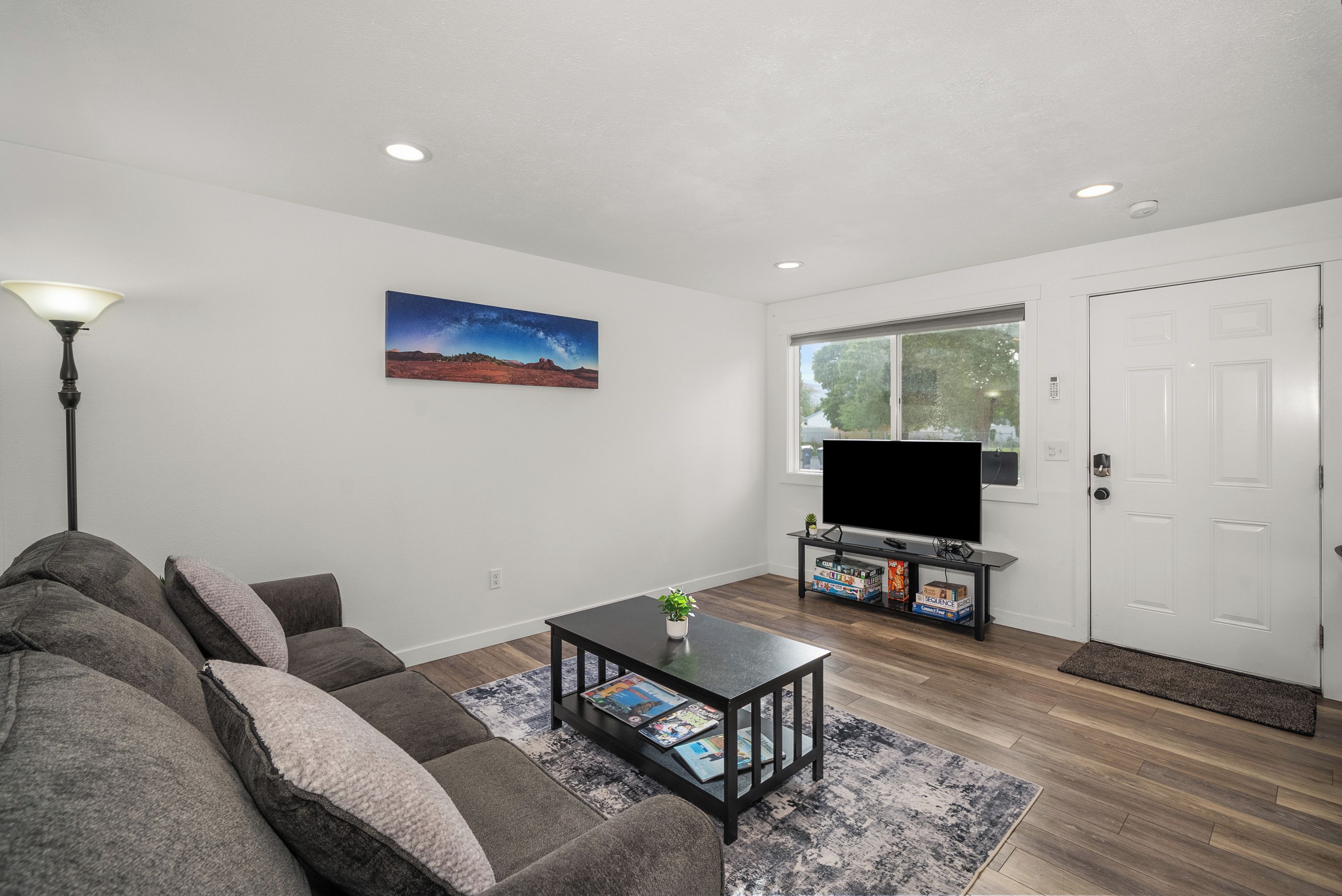 A living room with a sofa, a coffee table with magazines, a TV on a stand, and a painting on the wall.