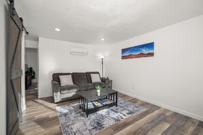 Una sala de estar con un sofá, una mesa de centro y un cuadro en la pared.