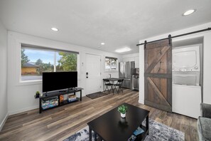 A modern kitchen with a large refrigerator, a sliding barn door, and a dining area with a table and chairs. - 💎 Great Find, 5 min to Browns Park 🛹💦🏀🏐 (Spokane Valley)
