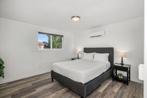 A bedroom with a bed, bedside tables, a window, and an air conditioning unit. - 💎 Great Find, 5 min to Browns Park 🛹💦🏀🏐 (Spokane Valley)