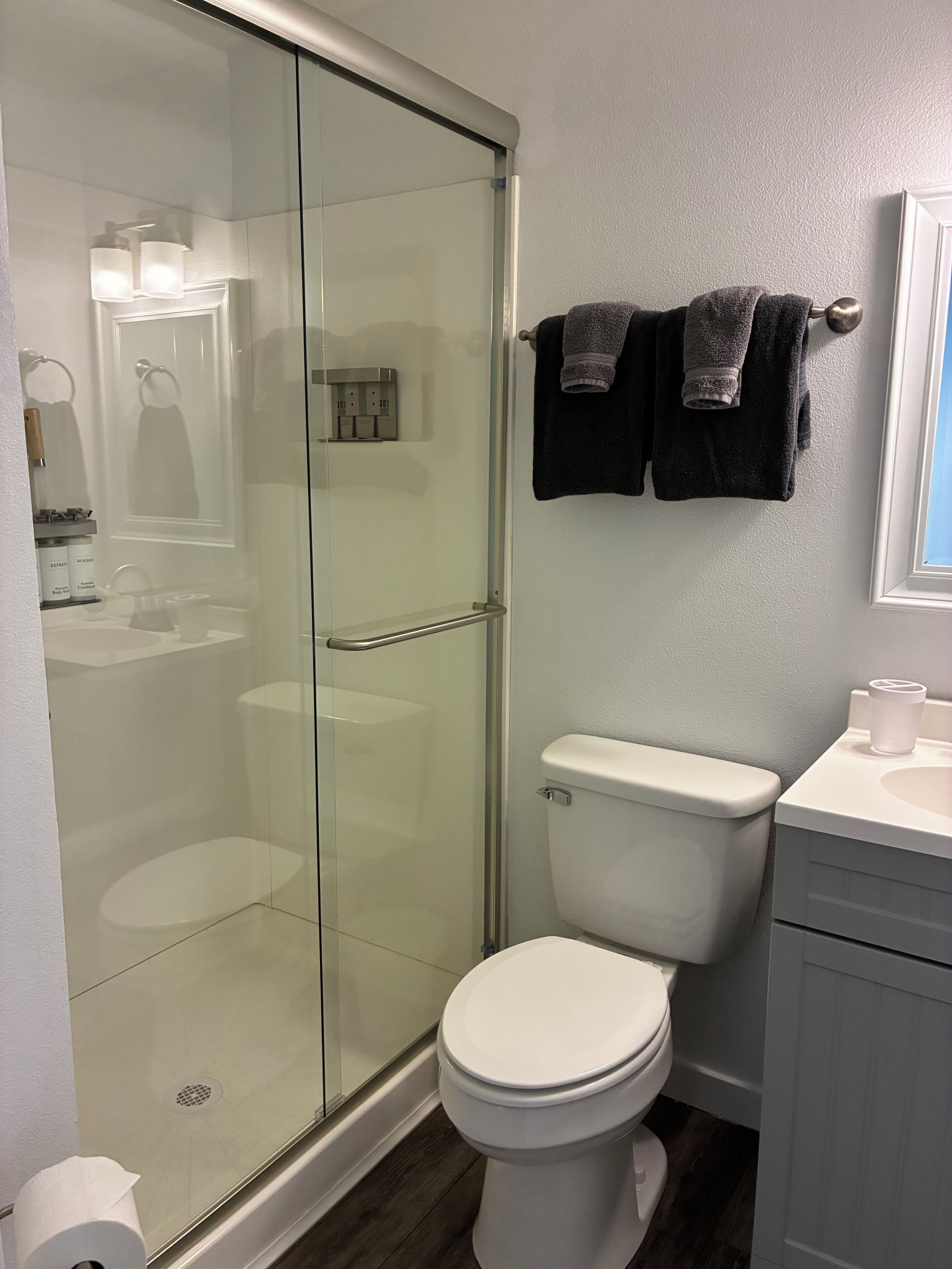 Une salle de bain moderne avec une douche à parois de verre, des toilettes blanches et un meuble-lavabo.