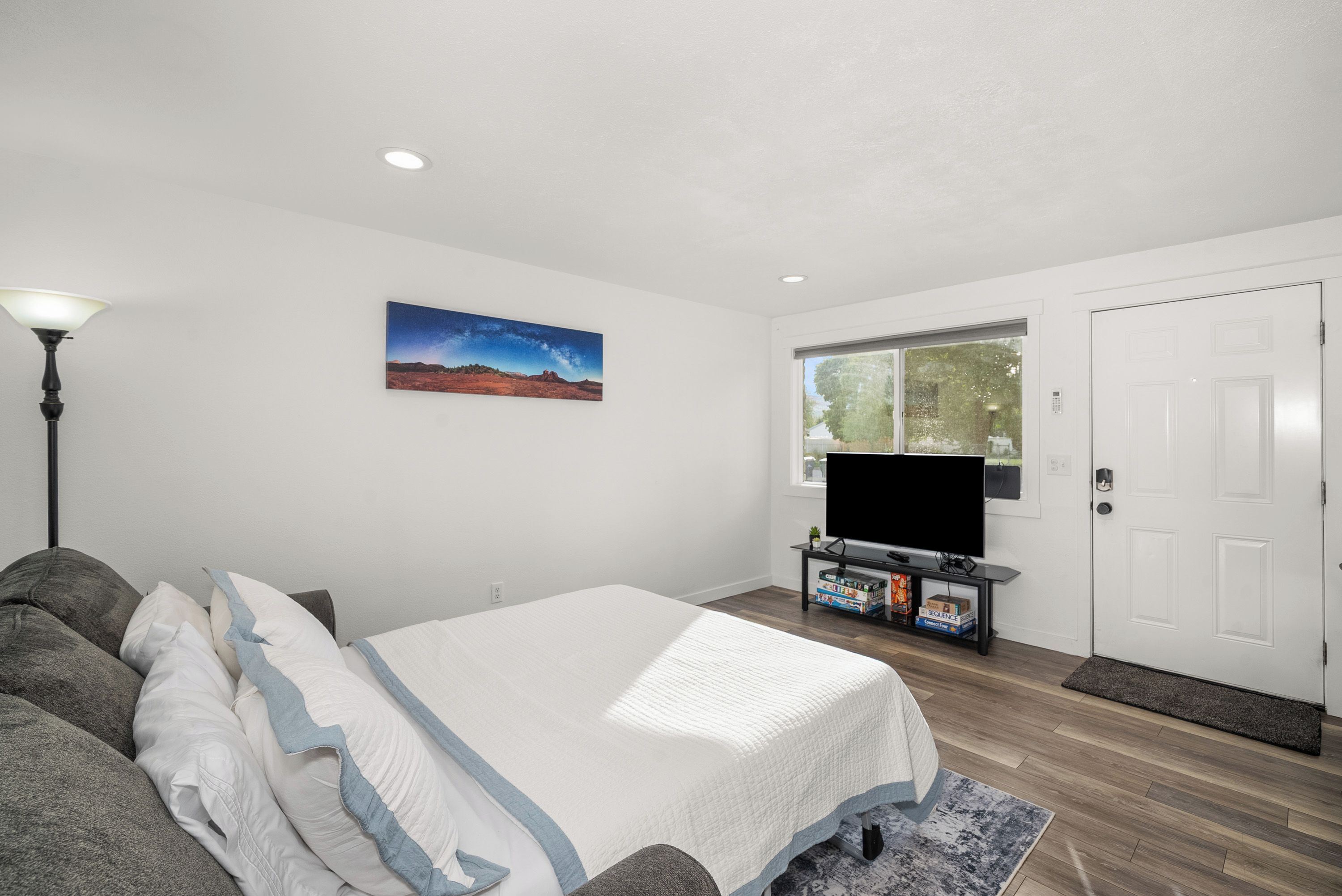 Une chambre à coucher avec un lit, une télévision, un tableau et une fenêtre.