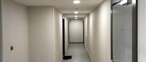 Un long couloir étroit doté d’un plafond perforé et d’un éclairage encastré.