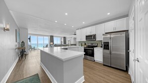 Una cucina moderna con mobili bianchi, elettrodomestici in acciaio inossidabile e una grande isola.