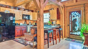 A rustic kitchen with wooden beams, a refrigerator, cabinets, a sink, and bar stools. - West Danville Cabin: Day Trip to Stowe Mtn! (West Danville)