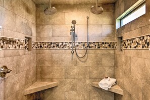 Eine Dusche mit gefliesten Wänden, einer Handbrause und einer fest installierten Duschbrause.