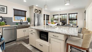 A modern kitchen with a central island, stainless steel appliances, and a view of the outside. - Dock Access: Waterfront Ocean City Home Near Beach (Ocean City)
