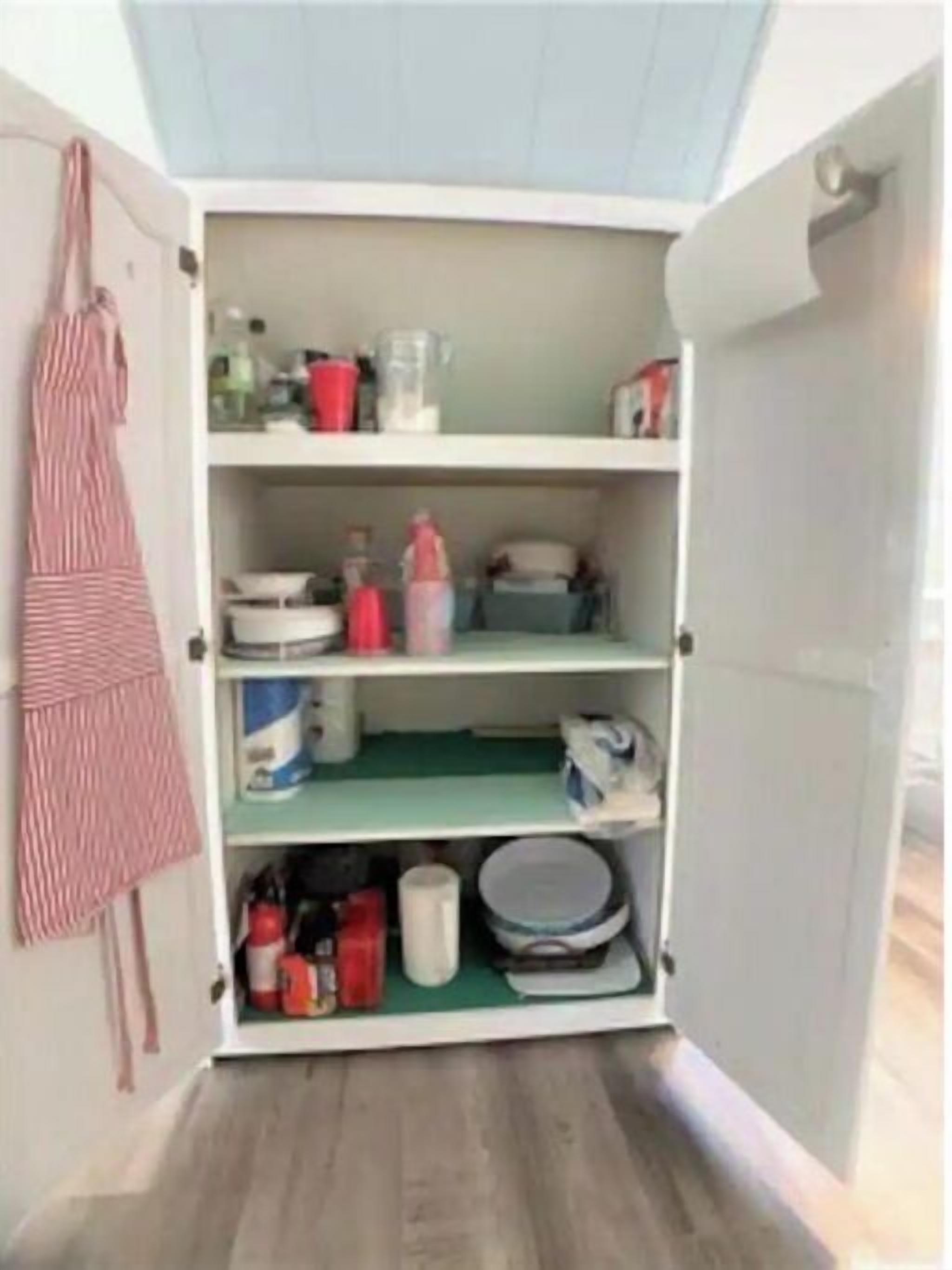 Cozinha com armários abertos e utensílios e eletrodomésticos diversos.