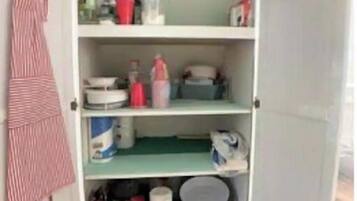 Cozinha com armários abertos e utensílios e eletrodomésticos diversos.
