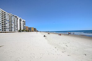 A beach with a hotel in the background.