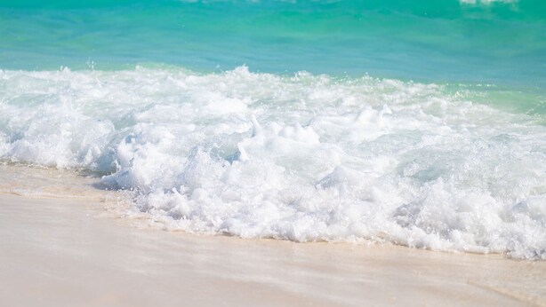 Een strand met golven die op het strand breken.