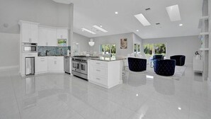 A modern kitchen with white cabinetry, a central island, and a large window providing natural light. - BY THE SEA VACATION VILLAS 5 STAR AZUL 3/2 PRIVATE POOL WALK TO BEACH (Fort Lauderdale)