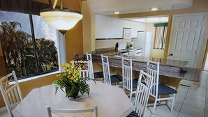 En matplats med ett runt bord, vita stolar och en krukväxt.