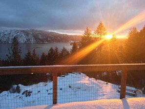 Eine verschneite Landschaft mit einem See, Bäumen und einem Holzzaun.