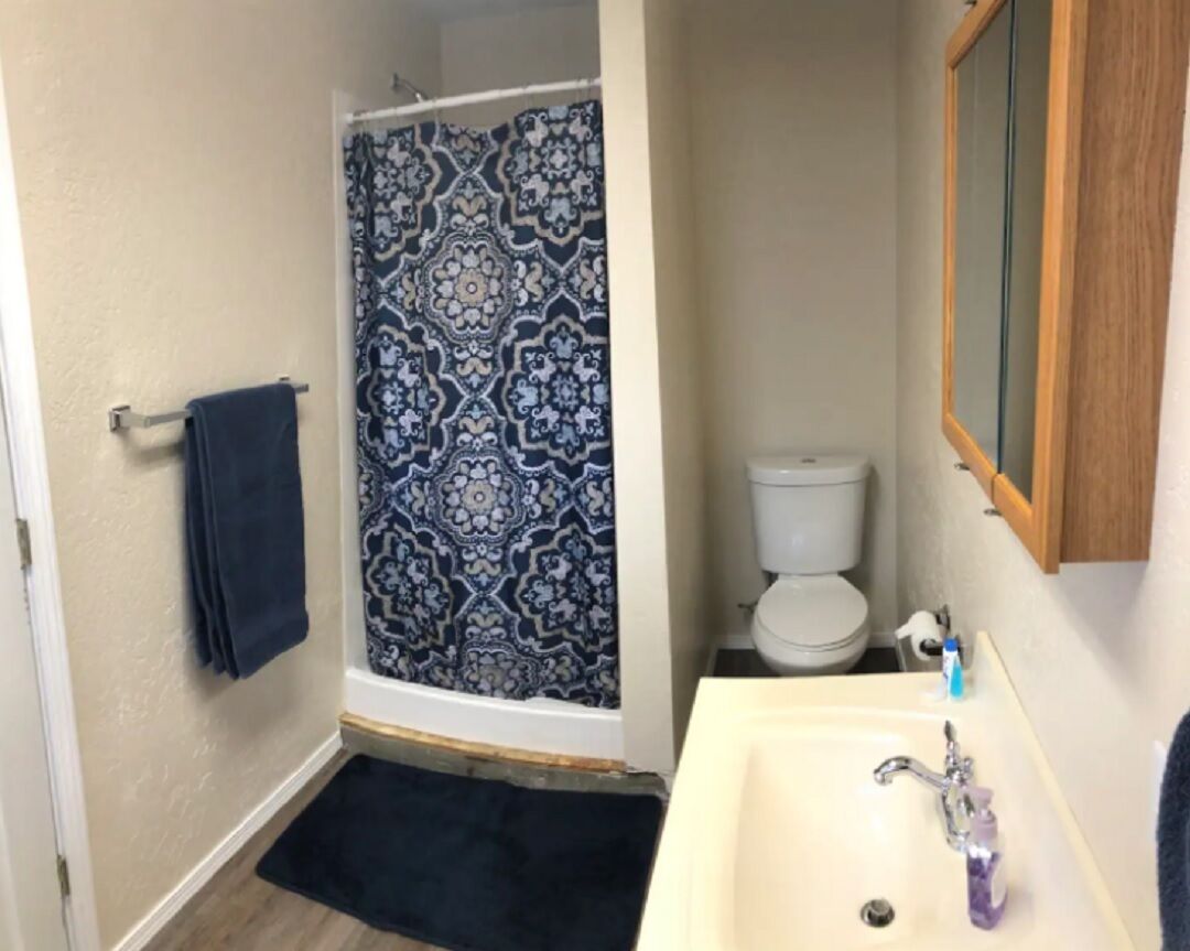 Un baño con ducha, inodoro, lavabo y un perchero para toallas.