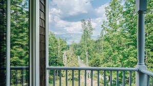 En balkon med udsigt over skov og bjerge.