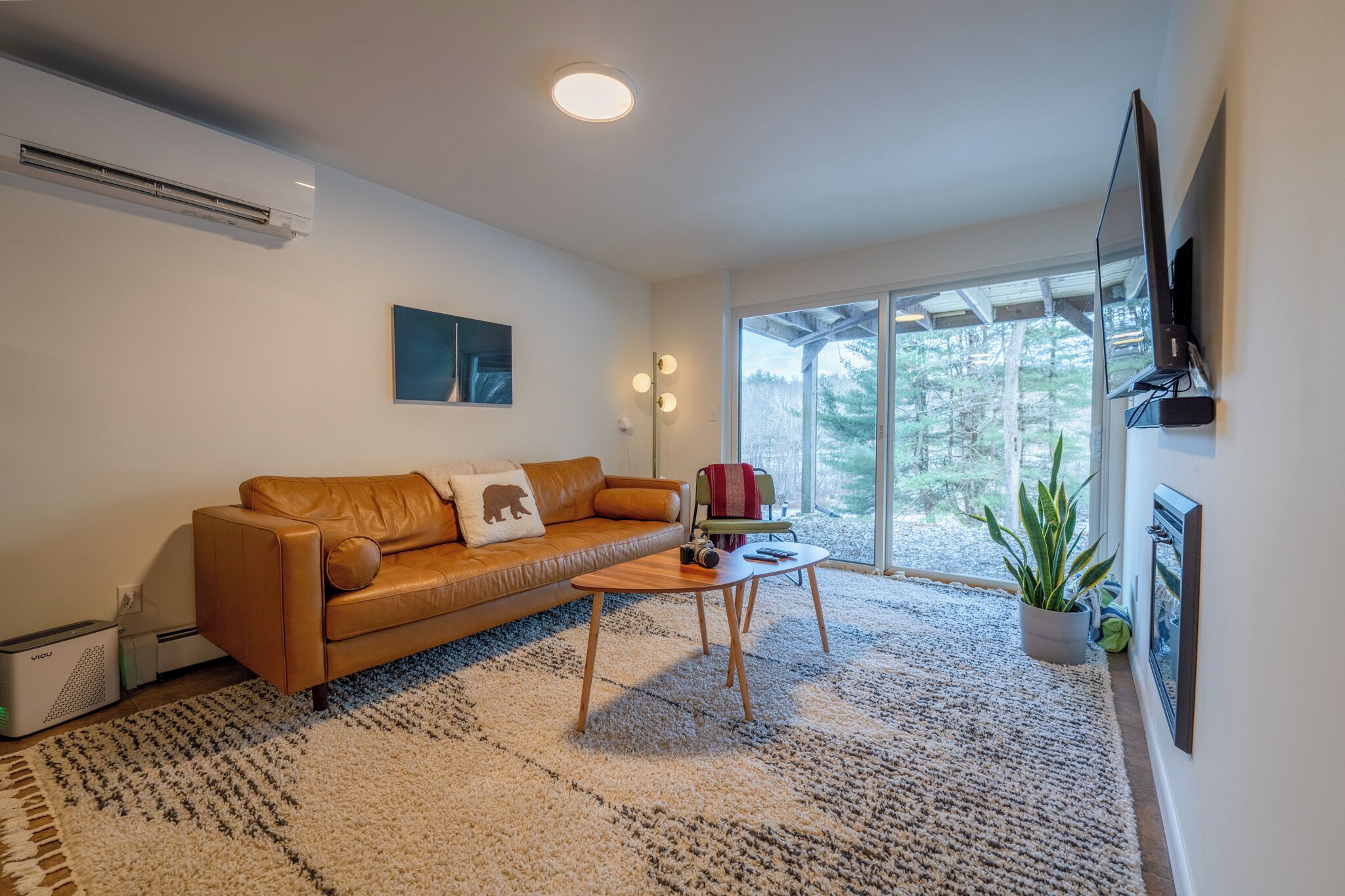 Una sala de estar moderna con un sofá de cuero, una mesa de centro y un ventanal con vistas a árboles.