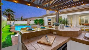 Eine Außenpatio mit Pool, Essbereich und einer Pergola mit Lichterketten.