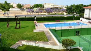 Ein Schwimmbecken mit grüner Veranda, umgeben von Rasen und einem Zaun.