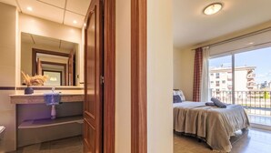 Een hotelkamer met een badkamer, een bed, een balkon en uitzicht op gebouwen.