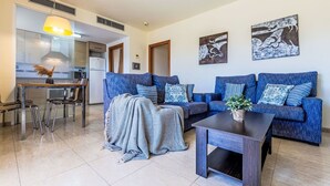 Een moderne woonkamer met een zithoek, een salontafel en een eethoek met stoelen.