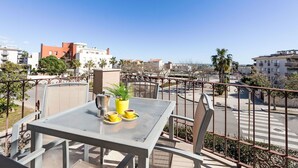 Een balkon met een tafel, stoelen, koffie en uitzicht op de stad.