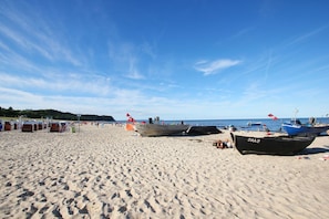 A sandy beach with several boats, including one labeled "BAA-23".