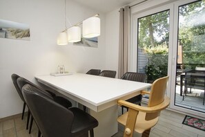 Un comedor moderno con una mesa blanca, sillas negras y de madera, e iluminación colgante.
