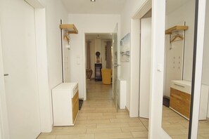 Un pasillo con un refrigerador blanco, un armario de madera y un espejo con un gabinete de madera.