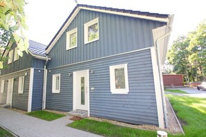 Une maison à deux étages, avec une façade bleue, des boiseries blanches et de nombreuses fenêtres.
