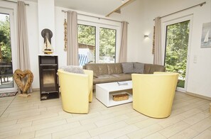 A living room with a sofa, two armchairs, a fireplace, and large windows.