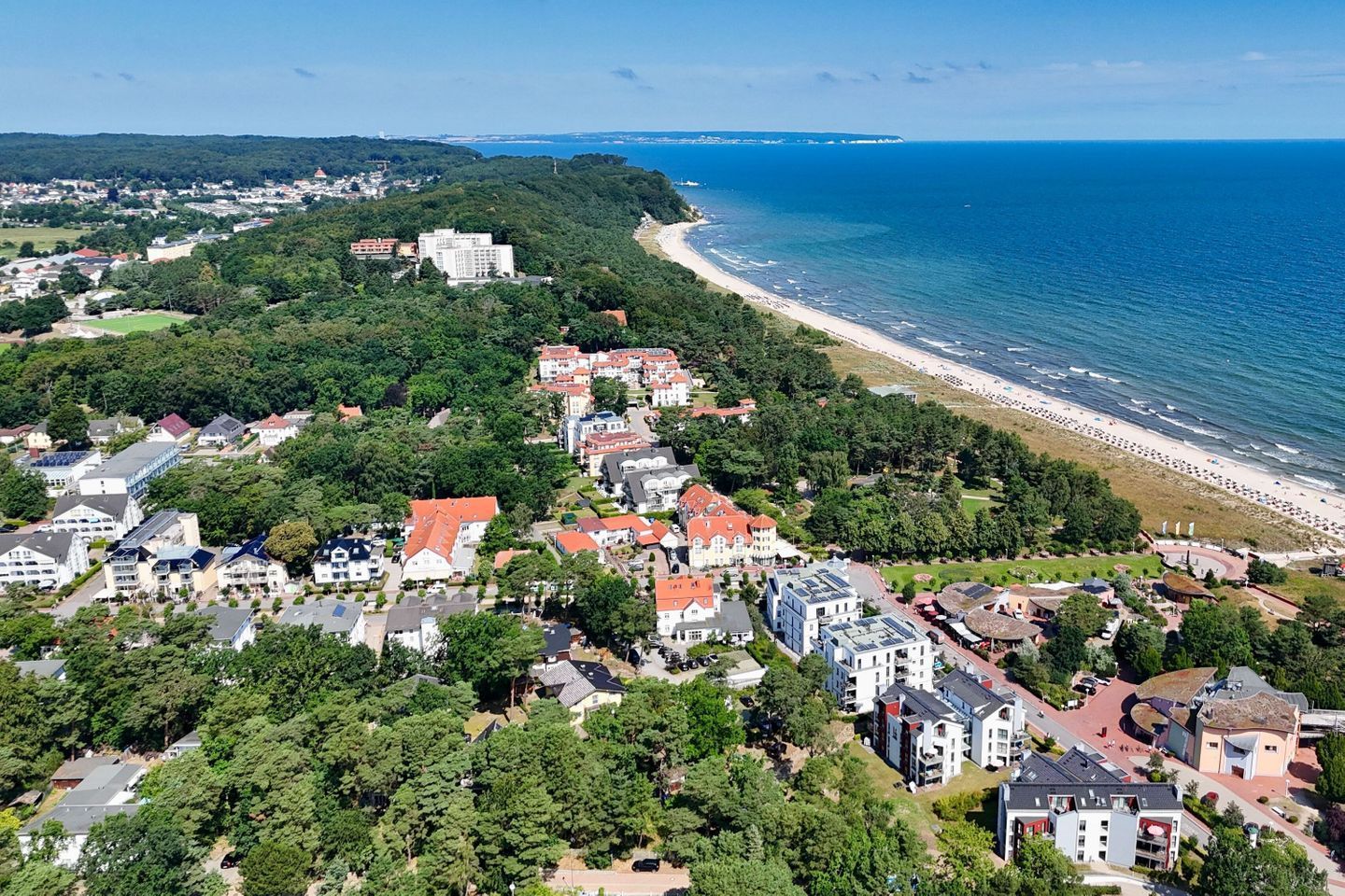 Vista aérea de un pueblo costero con edificios residenciales, una playa y una vista despejada del mar.