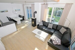 A modern living room with a black sofa, a white coffee table, and a dining area with a white table and chairs.