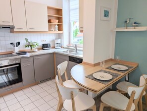 Une cuisine moderne avec un coin repas, comprenant une cuisinière, un four, un four à micro-ondes, une machine à café et une table à manger avec des chaises.