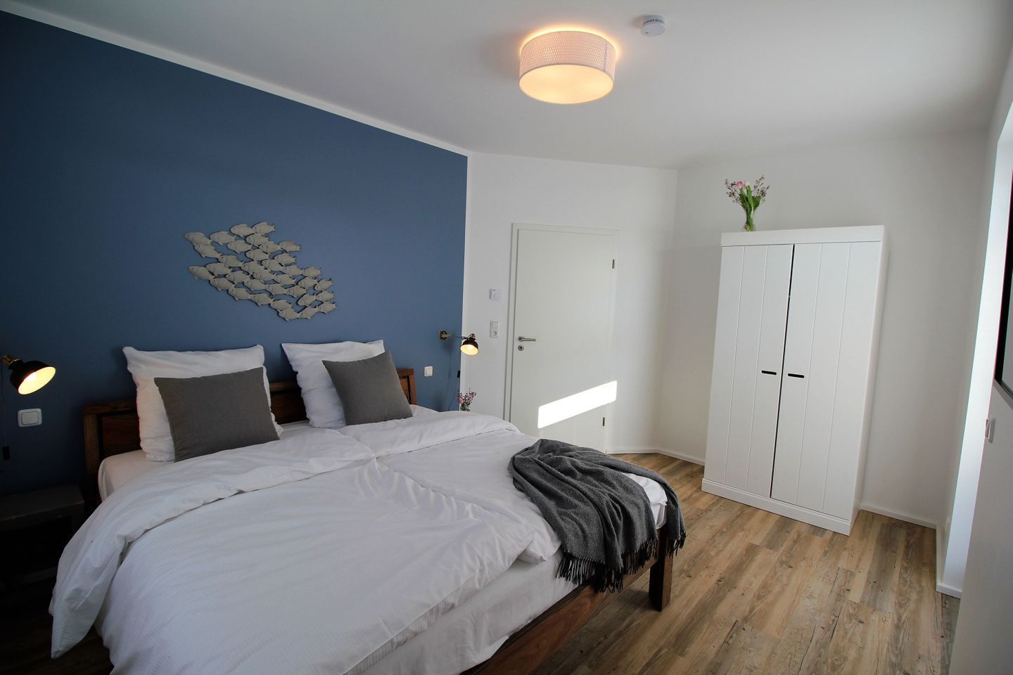 A bedroom with a bed, a wardrobe, a wall art piece, and a ceiling light.