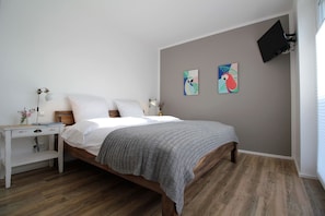 A bedroom with a bed, bedside table, lamp, and artwork on the wall.