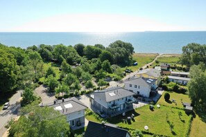 A coastal residential area with houses, a paved road, and a view of the sea.