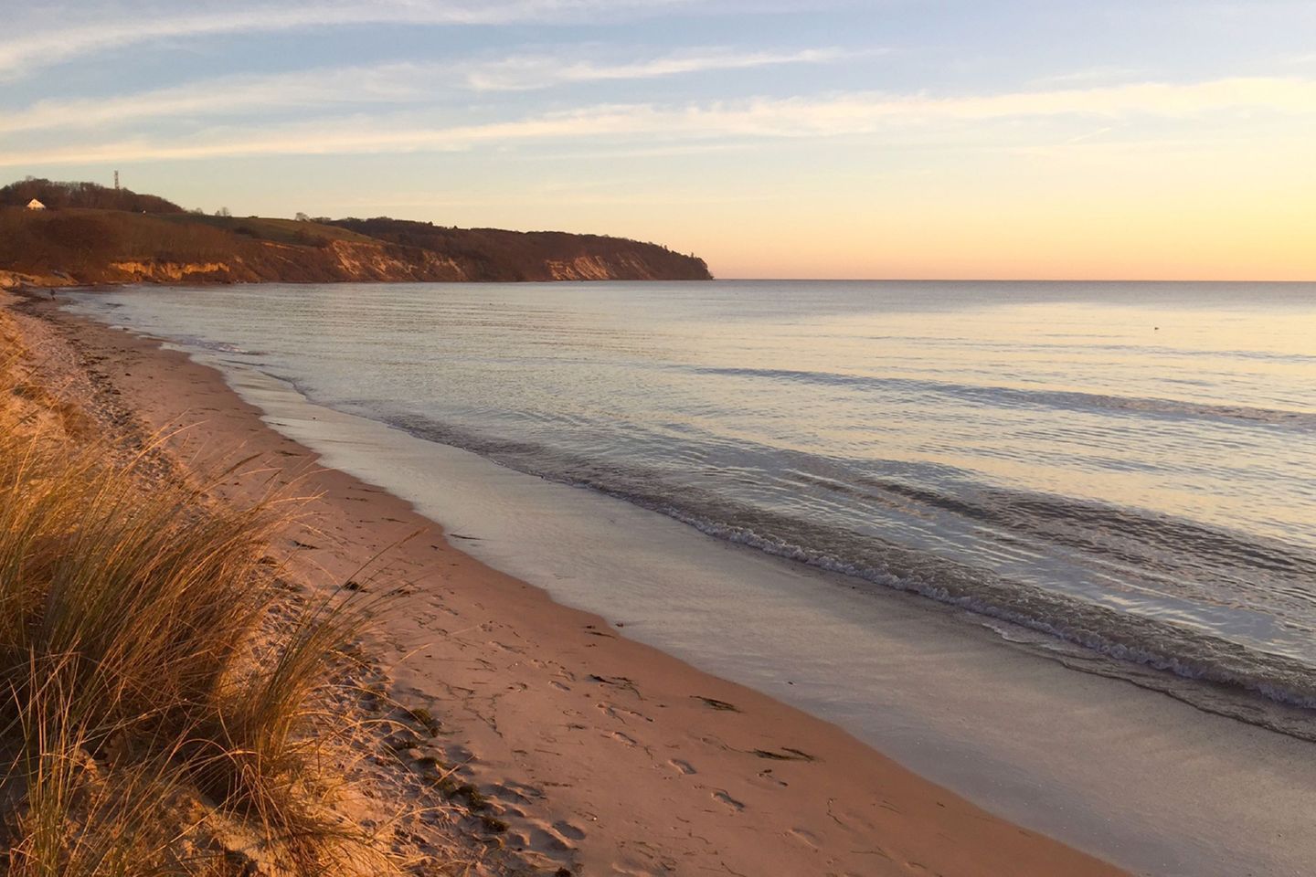 A beach with clear water, sandy shore, and a distant landmass.
