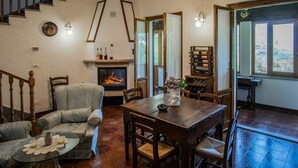 A cozy living room with a fireplace, a dining table, and a staircase. - Wonderful private villa for 7 guests with WIFI, private pool, TV, terrace and pets allowed (Anghiari)