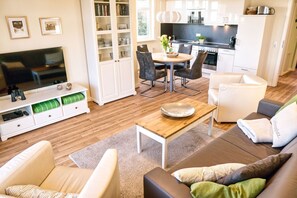 Un salon moderne avec un téléviseur, un canapé et un coin repas.