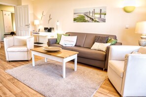 Un salon comprenant un canapé, deux fauteuils, une table basse et un tapis.