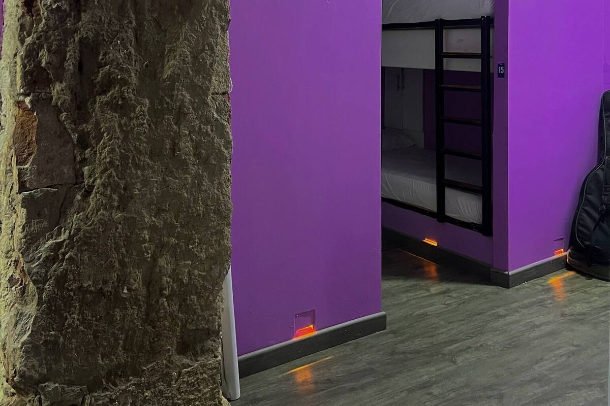 A room with purple walls, a bunk bed, and a stone pillar.